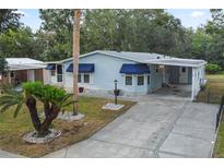 Charming single-story home with blue siding, awnings, and a well-maintained front yard at 522 Saint Andrews Blvd, Lady Lake, FL 32159