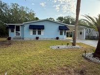 Charming blue home with awnings, white shutters, and meticulous landscaping at 522 Saint Andrews Blvd, Lady Lake, FL 32159