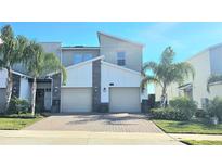 Modern two-story home with a paver driveway, two-car garage, and tropical landscaping at 817 Ocean Course Ave # 502, Davenport, FL 33896