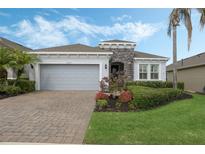 Charming single-story home featuring a stone accent wall, paver driveway, and well-manicured landscaping at 1027 Timbervale Trl, Clermont, FL 34715