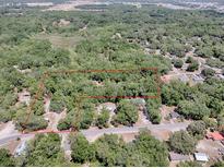 Aerial view of a tree covered residential area with a red boundary line over two lots at 1203 High St, Wildwood, FL 34785