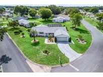Aerial view of a well-maintained home with lush lawn, mature trees, and a circular driveway in a quiet neighborhood at 17819 Se 105Th Ct, Summerfield, FL 34491