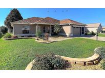 Beautifully landscaped front yard featuring a well-maintained lawn and colorful flower beds at 1914 Armondo Dr, The Villages, FL 32159