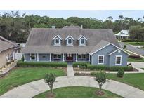 Charming single-Gathering home showcasing a well-manicured lawn, circular driveway, and inviting front porch at 19624 Spring Oak Dr, Eustis, FL 32736