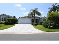 Charming single-story home featuring a spacious driveway, lush landscaping, and a welcoming two-car garage at 2120 Willow Grove Way, The Villages, FL 32162