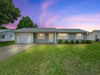 Charming single-story home features a well-manicured lawn, attached garage, and neutral-colored exterior at 2242 Orkney Dr, Leesburg, FL 34788