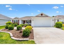 Charming single-story home with well-manicured landscaping and a two-car garage on a sunny day at 3118 Sweetgum St, The Villages, FL 32163