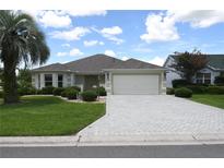 Charming single-story home with a well-manicured lawn, beautiful landscaping, and a paved driveway leading to a two-car garage at 3177 Williams Rd, The Villages, FL 32162