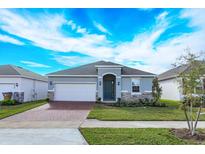 Charming single-story home featuring a well-manicured lawn, brick driveway, and an attached two-car garage at 5006 Abigail Dr, Lake Wales, FL 33859