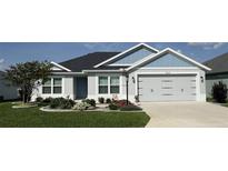 Charming single-story home with a manicured lawn, gray exterior paint, and a two-car garage at 6633 Holovak Ter, The Villages, FL 34762