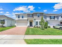 Beautiful two-story home with manicured lawn, brick driveway, and welcoming front entrance at 678 Blackstone St, Minneola, FL 34715
