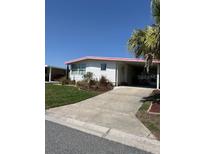 Well-maintained home featuring an attached carport, tidy landscaping, and mature trees at 715 Surrey Pl, Leesburg, FL 34748