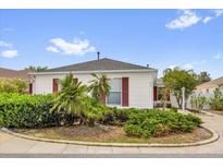 Charming home featuring well-maintained landscaping, red shutters, and a circular driveway at 8932 Se 168Th Sedgwick Pl, The Villages, FL 32162