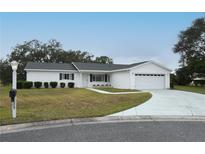 Charming single-story home featuring a well-maintained lawn and two-car garage at 10442 Se 179Th Pl, Summerfield, FL 34491