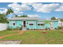 Charming single-story home with a light blue exterior, brick pathway, and well-maintained landscaping at 1301 North Ave, Tavares, FL 32778