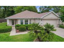 Charming single-story home with well-maintained landscaping, complemented by a two-car garage and inviting walkway at 13050 Se 89Th Cir, Summerfield, FL 34491