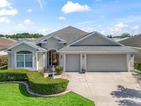 Charming single-story home boasts a three-car garage, lush landscaping, and a welcoming front entrance at 1642 Pennecamp Dr, The Villages, FL 32162