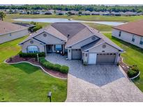 Beautiful home featuring a manicured lawn, paver driveway, and stunning water views at 17563 Se 122Nd Ter, Summerfield, FL 34491