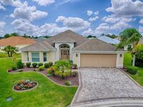 Beautiful single-story home featuring a paver driveway, manicured landscaping, and a neutral-colored exterior at 2044 Larkwood Ct, The Villages, FL 32162
