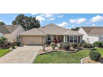 Charming single-story home featuring well-manicured landscaping and a brick-paved driveway at 2096 Callaway Dr, The Villages, FL 32162