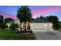 Charming single-story home with a three-car garage, palm tree, and well-maintained landscaping at 2125 Horizon Run, The Villages, FL 32162