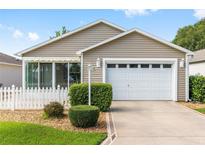 Charming single-story home featuring a well-manicured lawn and a white picket fence at 2564 Red Cedar Ln, The Villages, FL 32162