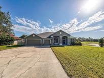 Charming single-story home with a three-car garage, well-manicured lawn, and lovely landscaping at 33818 Venice Ln, Sorrento, FL 32776