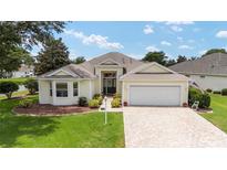 Charming single Gathering home featuring a well-maintained lawn, 2 car garage and covered entryway at 616 Hartford Ln, The Villages, FL 32162