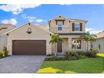 Charming two-story home featuring stone accents, a paved driveway, and meticulously landscaped front yard at 674 Anna Ridge Rd, Minneola, FL 34715