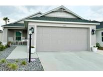 Charming home showcasing a clean two-car garage and well-maintained front yard with manicured rock landscaping at 7394 Lussier Ct, The Villages, FL 34762