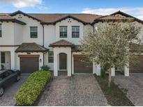 Charming townhome with well-maintained landscaping, a brick driveway and a two car garage at 1342 Royal Saint George Blvd, Davenport, FL 33896