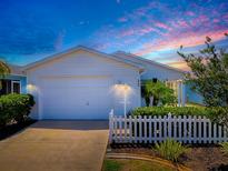 Charming single-story home featuring a white picket fence and an attached two-car garage at 1722 Moreno Pl, The Villages, FL 32159