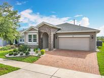 Charming home with stone archway, brick driveway, and fresh landscaping under a bright blue sky at 224 Silver Maple Rd, Groveland, FL 34736