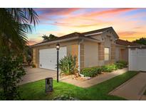 Attractive single-story home with a two-car garage, manicured lawn, and colorful sunset sky at 2744 Gresham Ave, The Villages, FL 32162