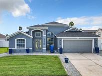 Beautiful blue two-story home featuring manicured lawn, a two-car garage, and modern architectural details at 310 Ballyshannon Dr, Davenport, FL 33897