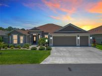 Beautiful home with a three-car garage and well-manicured lawn at sunset at 3138 Aurea Pl, The Villages, FL 32163