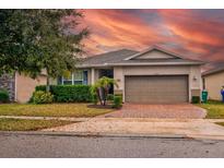 Charming single-Gathering home with a brick driveway, landscaping, and beautiful sunset sky at 3194 Bayou Ln, Tavares, FL 32778