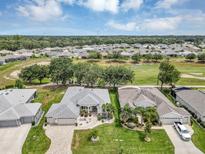 Expansive aerial view of community with lush landscaping, golf course, and single-story homes under a partly cloudy sky at 3677 Arlington Ridge Blvd, Leesburg, FL 34748