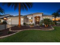 Well-manicured lawn and mature landscaping enhance this single-story home's curb appeal with elegant entry at 4033 Swaying Palm Ct, The Villages, FL 32163