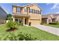 Two-story home featuring a manicured front yard and a spacious driveway leading to an attached two-car garage at 422 Rock Springs Cir, Groveland, FL 34736