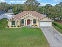 Inviting single-story home featuring a well-manicured lawn, attached garage, and decorative front columns at 847 Cumberland Cir, Minneola, FL 34715