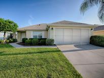 Traditional single-story home features a well-manicured lawn, lush shrubs, and an attached two car garage at 8601 Se 133Rd St, Summerfield, FL 34491
