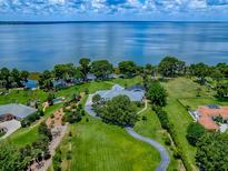 Expansive lakefront property with a well-manicured lawn, mature trees, and stunning water views at 11226 Lane Park Rd, Tavares, FL 32778