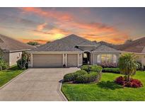 Charming single-story home features a two-car garage, meticulously manicured landscaping, and a cozy front porch at 1304 Zombar Pl, The Villages, FL 32163