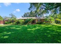 Charming single-story brick home with a manicured lawn and mature landscaping including palm trees at 15935 J And J Dr, Tavares, FL 32778