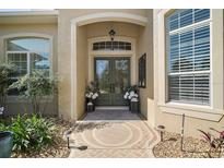 Inviting entryway with double doors, stylish decor, and neutral color scheme. Landscaped for curb appeal at 2204 Baypoint Way, The Villages, FL 32162