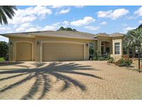 Lovely single story home featuring a three-car garage, desert landscaping, and a brick paved driveway at 2204 Baypoint Way, The Villages, FL 32162