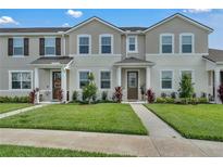 Attractive two-story townhome showcasing manicured lawn, neutral colors, and covered entryway at 2552 Chickasaw Plum Loop, Clermont, FL 34711