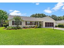 Charming single-story home boasts lush landscaping, a screened garage, and a beautifully maintained lawn at 26608 Racquet Cir, Leesburg, FL 34748