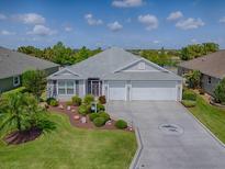 Well-maintained single-story home featuring a landscaped front yard, concrete driveway, and three-car garage at 3136 Vandenberg Ct, The Villages, FL 32163